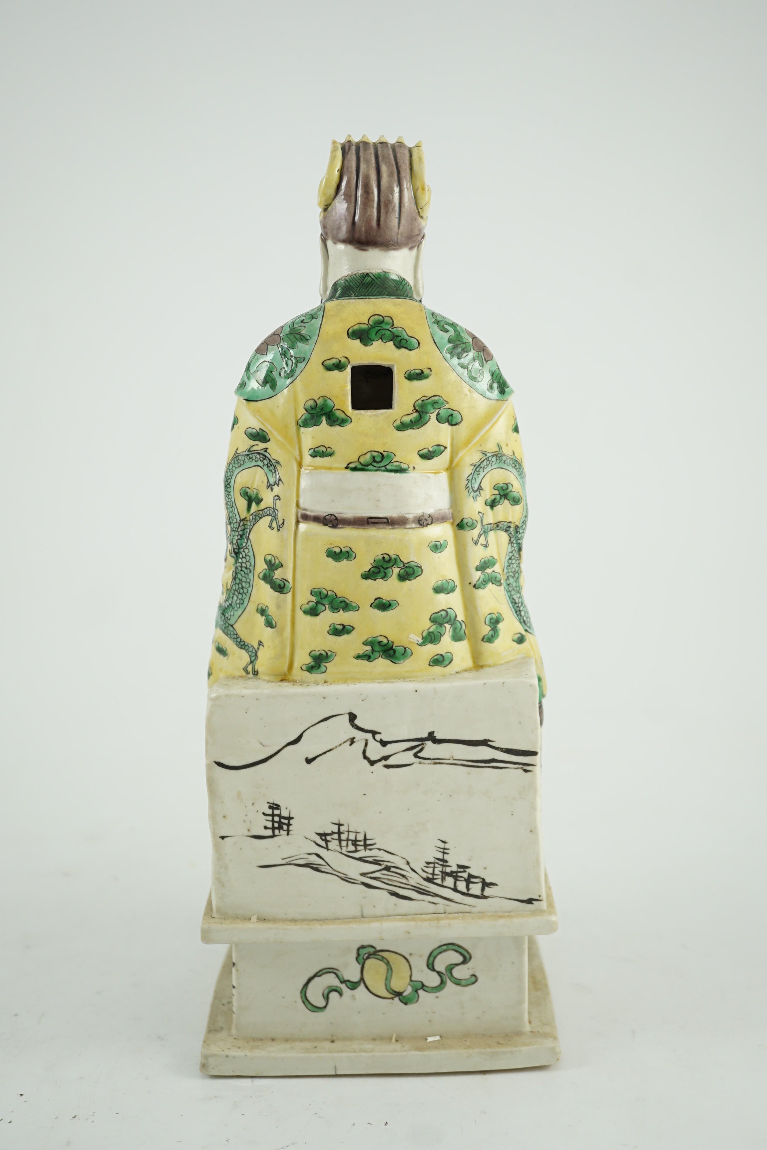A Chinese enamelled biscuit figure of a seated court official, Kangxi period, 31.5cm high, small losses